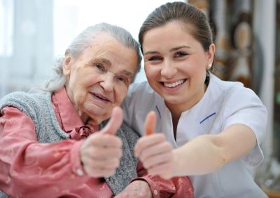Happy caregiver and client giving a thumbs up