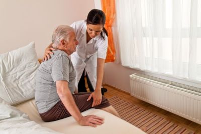 Caregiver giving client help out of bed