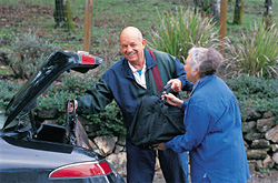 Man helping woman at the trunk of her car.